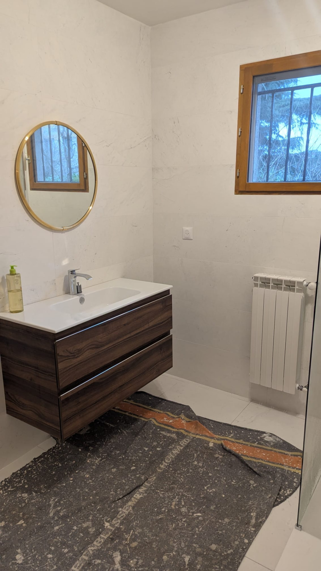Meuble vasque finition bois et miroir rond après rénovation